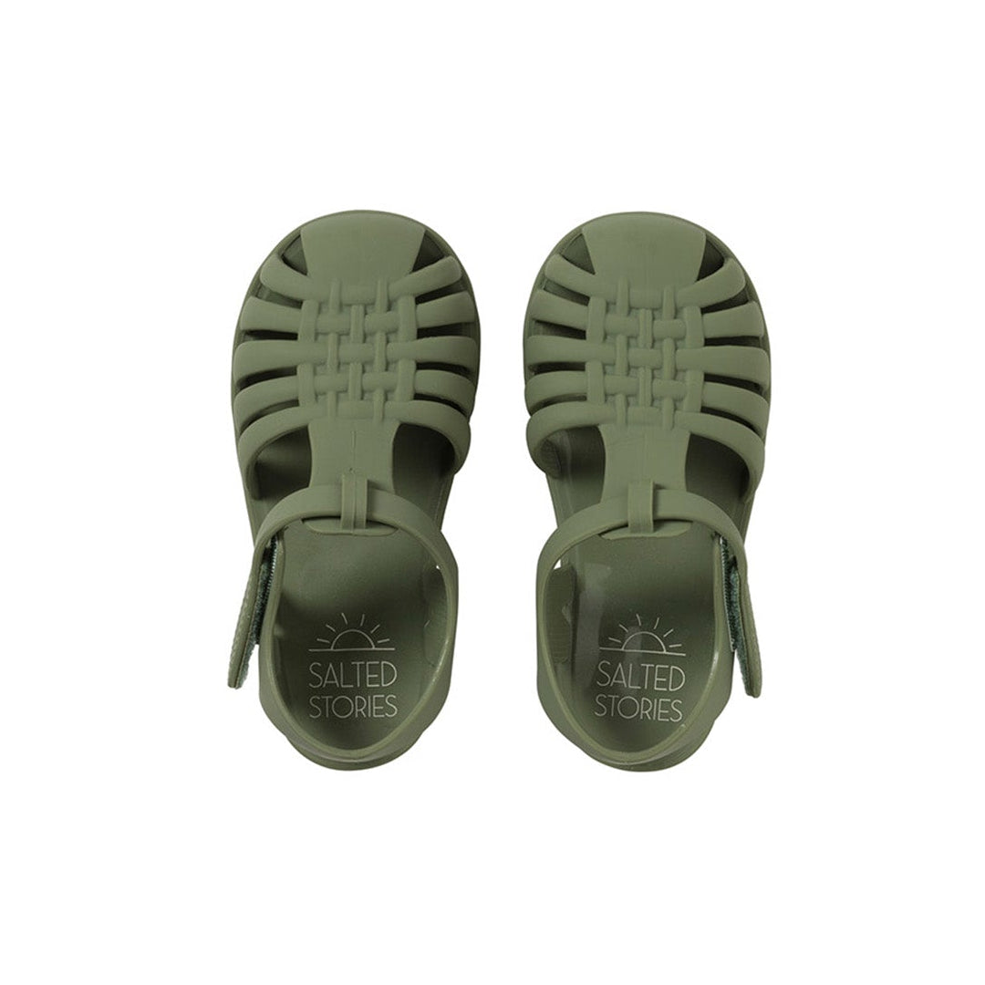 Pair of green sandals with 'Salted Stories' branding on a white background