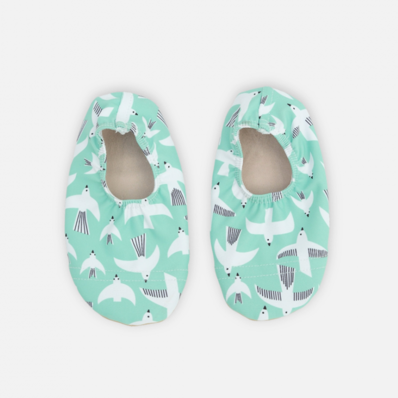 Pair of green baby shoes with animal pattern on a white background