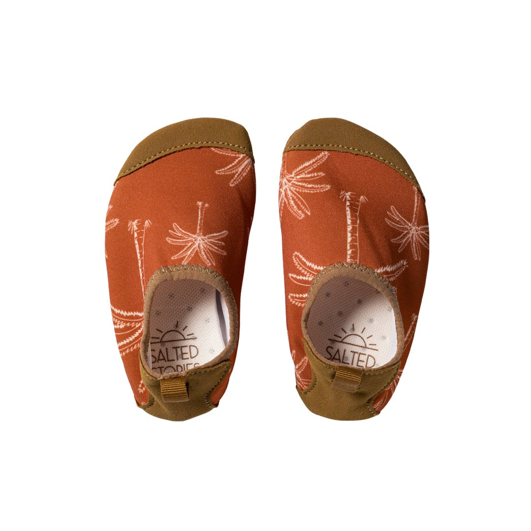 Pair of orange sandals with white patterns on a white background