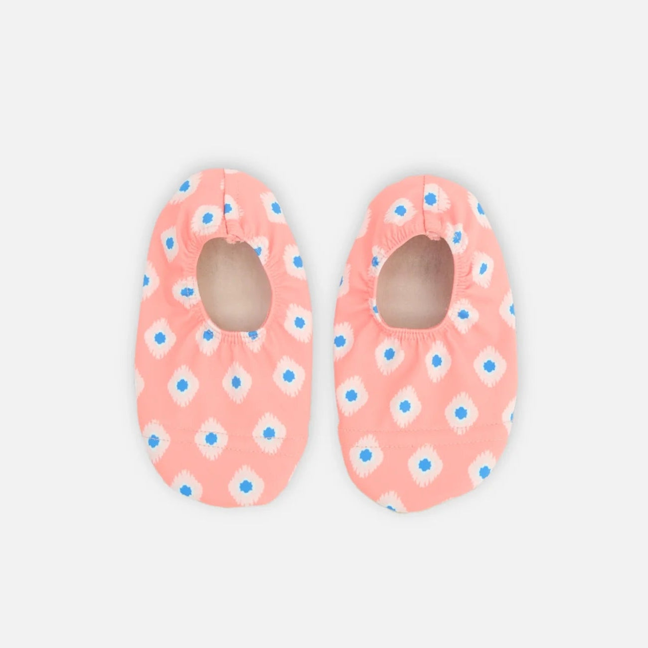 Pair of pink baby shoes with blue floral patterns on a light gray background