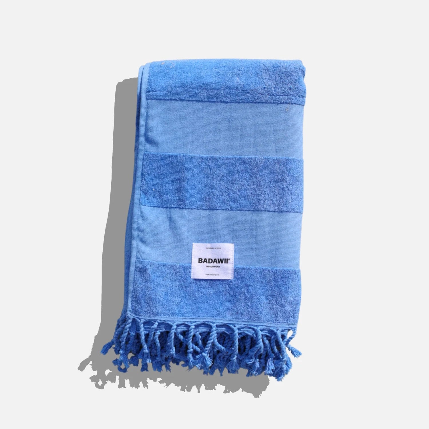 Blue striped towel with tassels on a light gray background