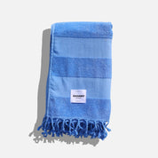 Blue striped towel with tassels on a light gray background